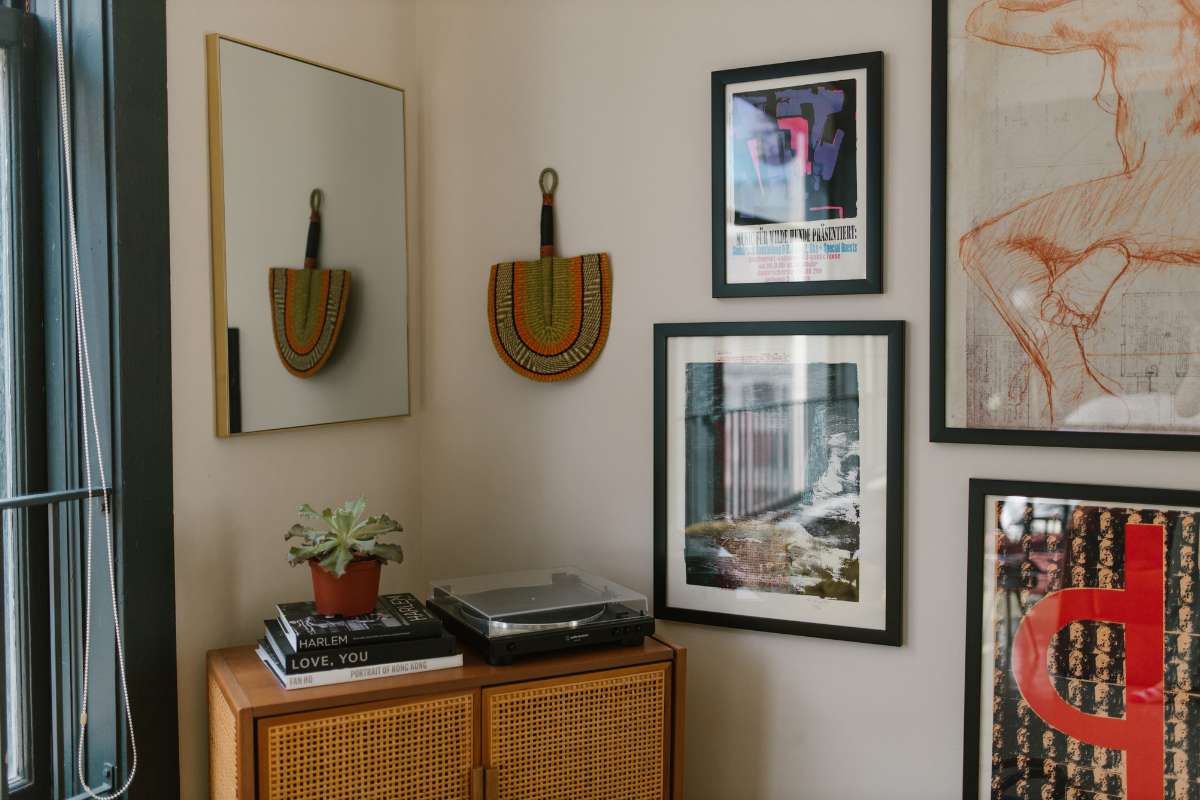 Una habitación con una mesa de madera, un espejo y varias fotos enmarcadas en las paredes.