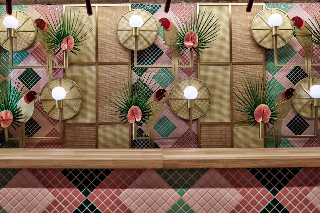 Muro colorido adornado con palmeras y un bar, creando un ambiente tropical y vibrante.