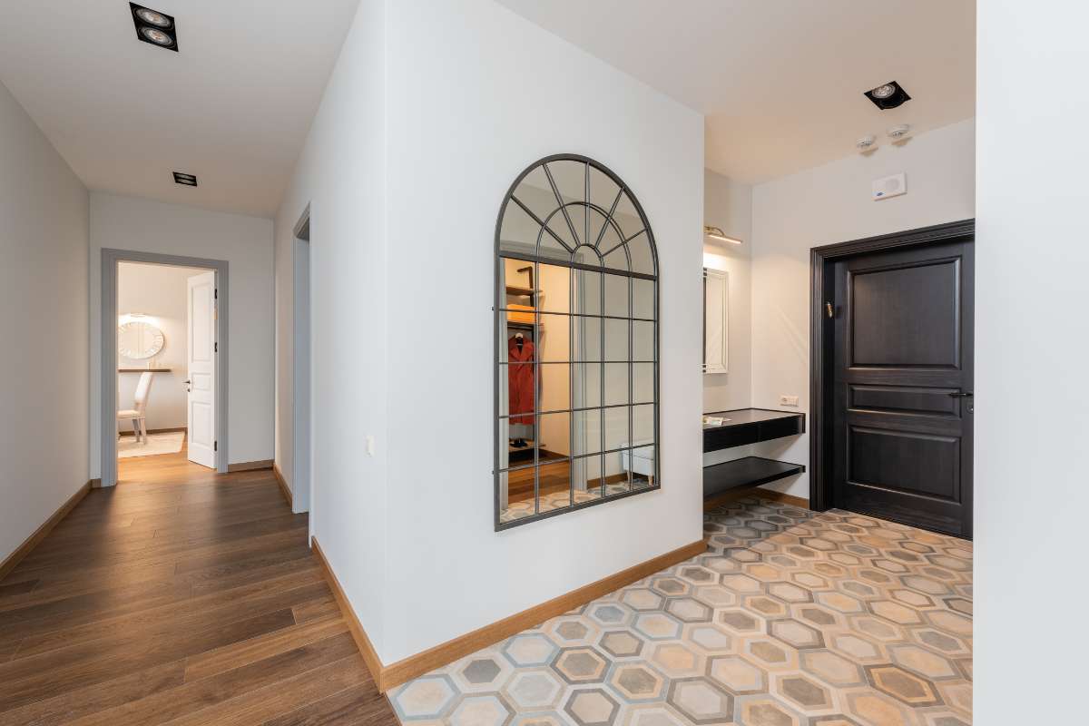 Pasillo con un espejo y suelos de madera, creando un ambiente elegante y acogedor.