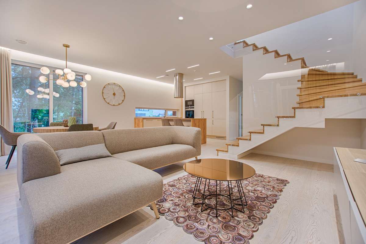 Sala de estar moderna con una escalera elegante y un sofá cómodo, creando un ambiente acogedor y contemporáneo.