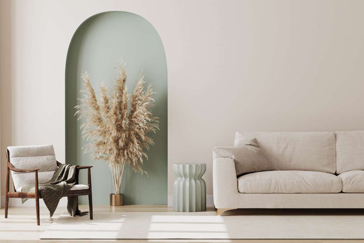 Sala de estar con un sofá, una silla y un jarrón decorativo en un ambiente acogedor y bien iluminado.