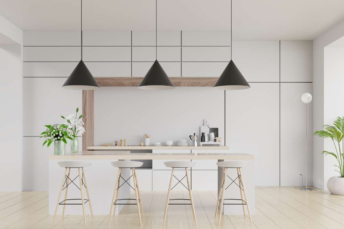 Cocina moderna con paredes blancas y lámparas colgantes negras, creando un ambiente elegante y contemporáneo.