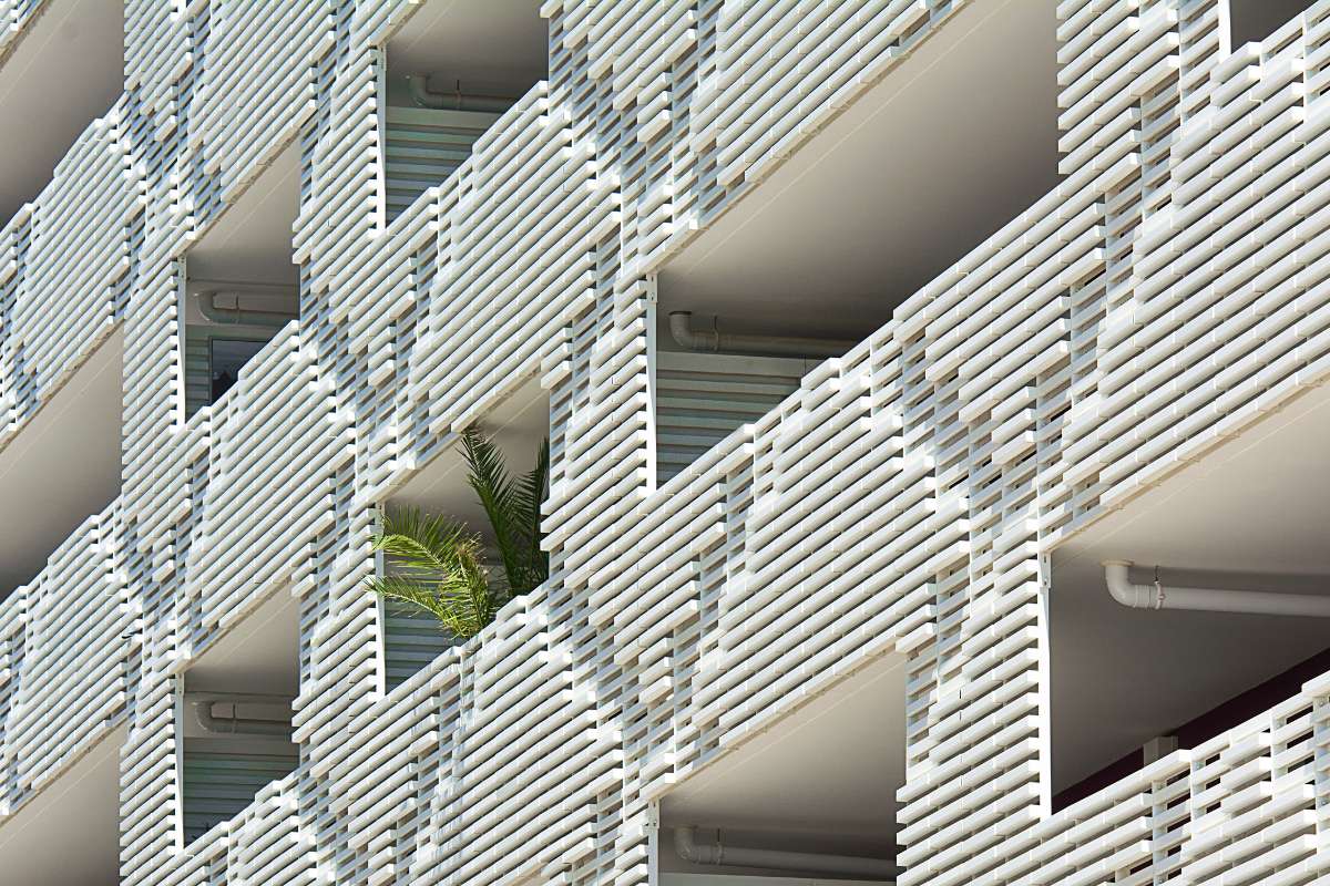 Edificio de ladrillos blancos rodeado de plantas en el exterior, mostrando un ambiente natural y armonioso.