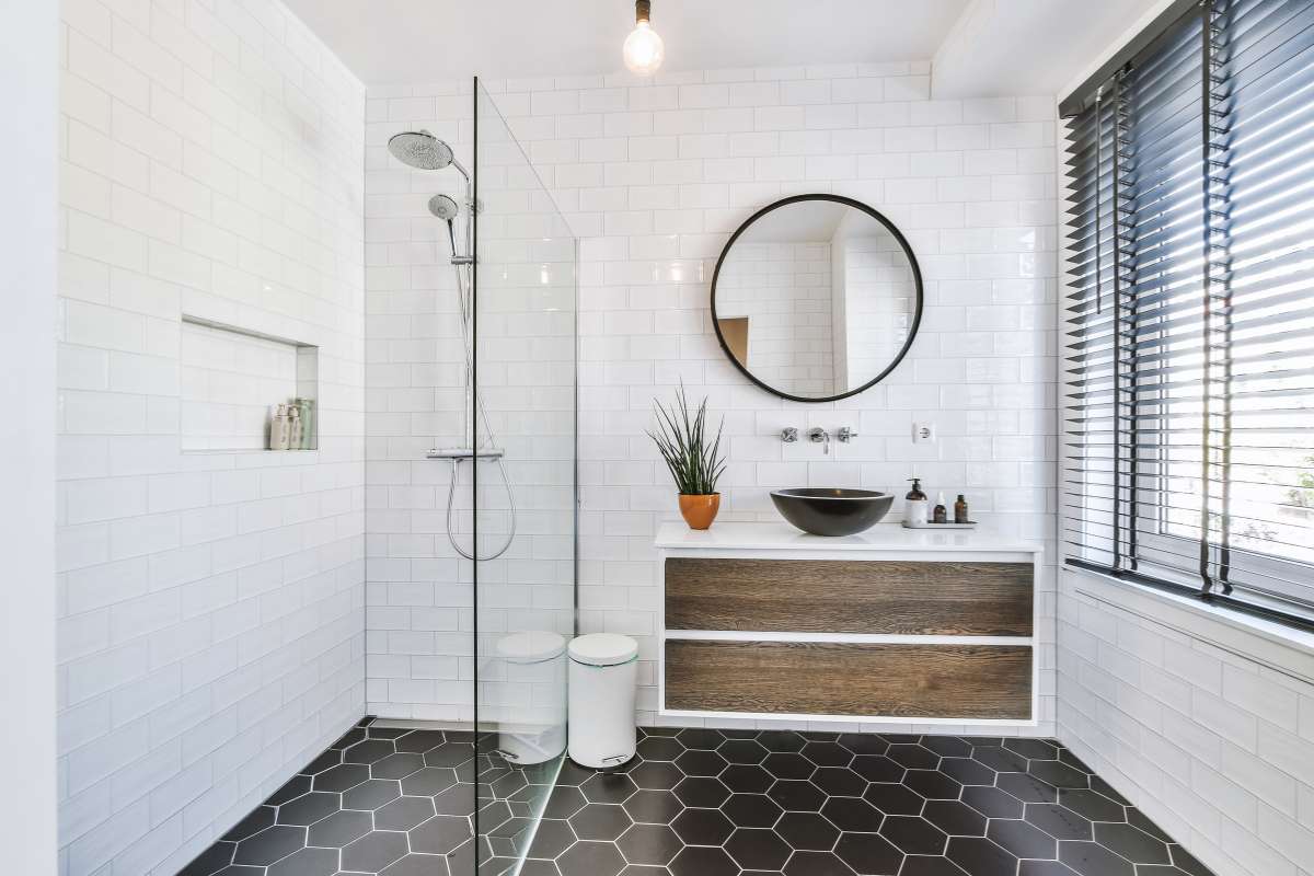 Baño con azulejos en blanco y negro y un espejo redondo que refleja un ambiente elegante y moderno.