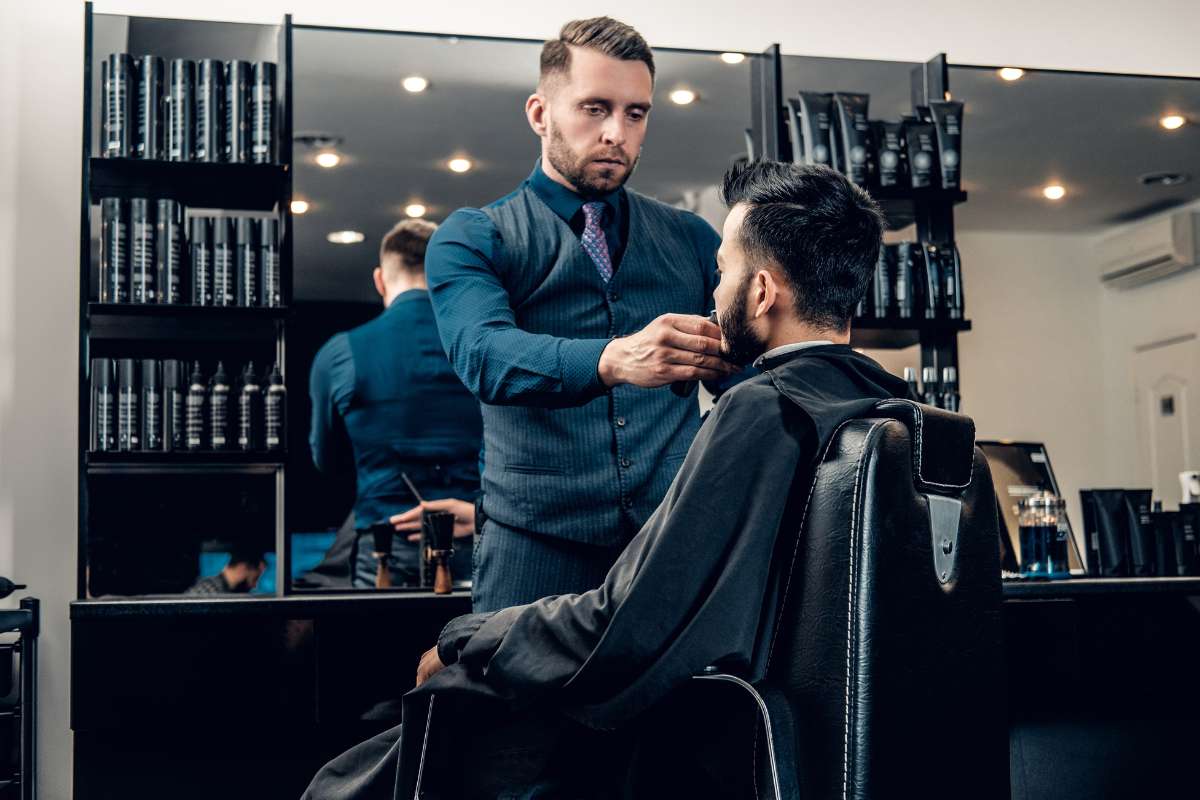 Un hombre recibe un corte de cabello por parte de un barbero en un ambiente de peluquería.