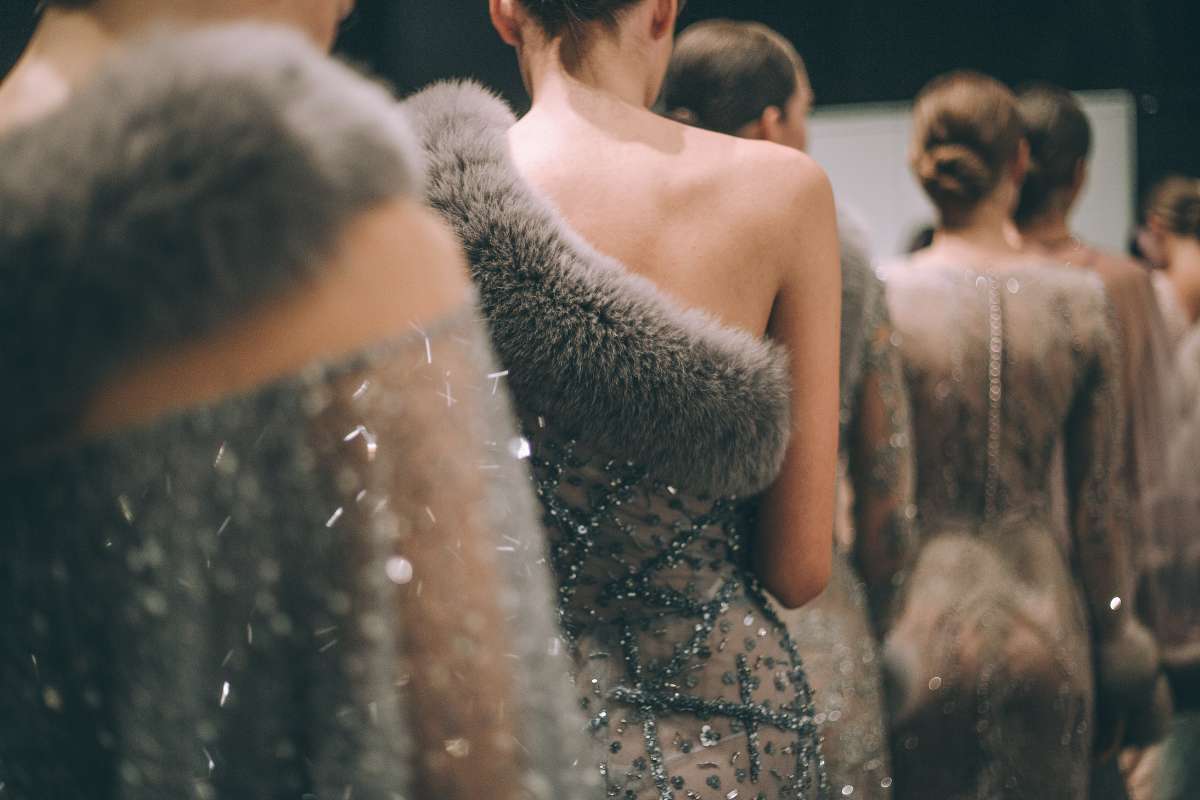 Modelos luciendo vestidos con cuellos y puños de piel, exhibiendo elegancia y sofisticación en la pasarela.