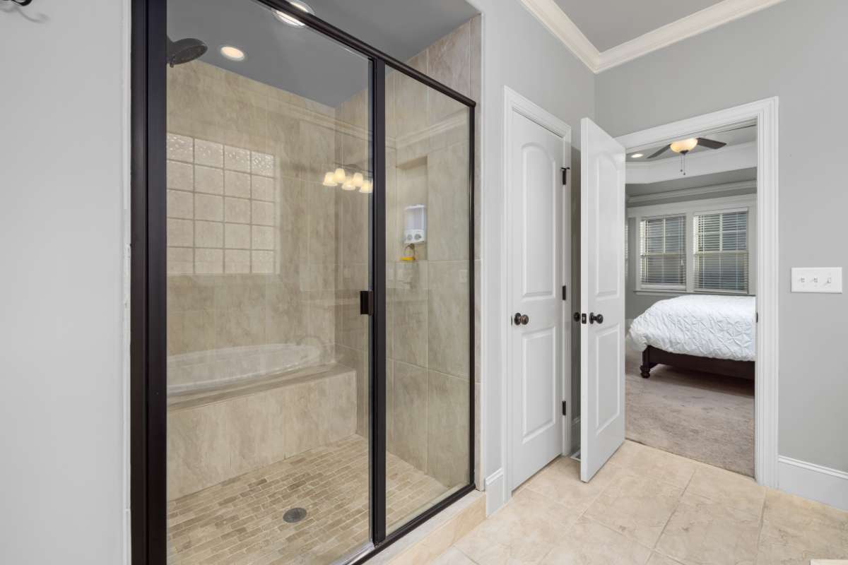 Baño moderno con ducha a ras de suelo y bañera, decorado con azulejos elegantes y luz natural.